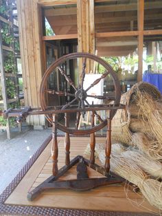 an old spinning wheel on top of a wooden table next to hay and other items