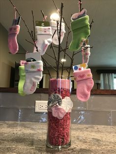 a vase filled with baby's socks hanging from a tree on a counter top