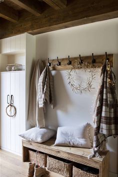 a wooden bench sitting in front of a coat rack filled with blankets and pillows on top of it