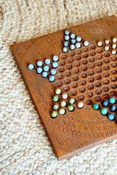 a wooden board game set with marbles and beads on the board, ready to play