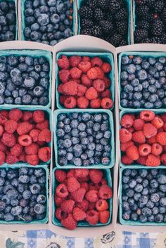 berries, raspberries and blueberries are arranged in baskets