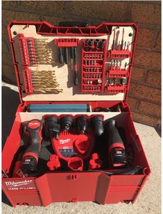 a red tool box filled with tools sitting on top of a sidewalk