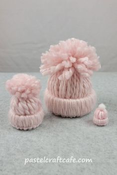 a pink knitted hat and booties with pom - poms on top