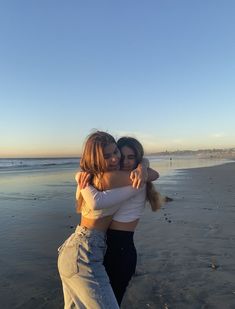 two women hugging each other on the beach