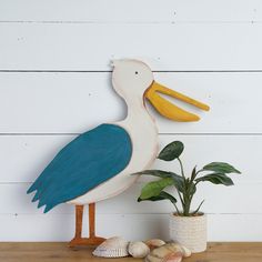 a white and blue pelican standing next to some seashells