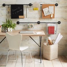 a desk with a chair, potted plant and other office supplies on it in front of a white brick wall