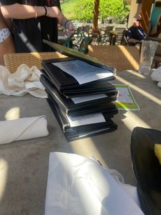 a stack of papers sitting on top of a table next to a person holding a knife