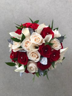 a bridal bouquet with red and white flowers in it's center, on a gray background