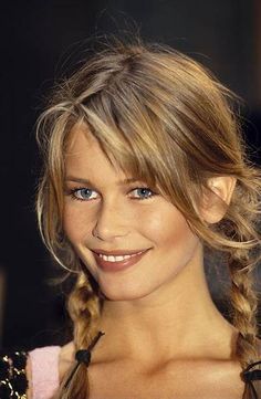 a woman with long hair and braids smiling at the camera while wearing a black dress