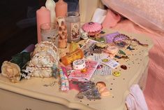 an assortment of items are sitting on a small table next to a pink comforter