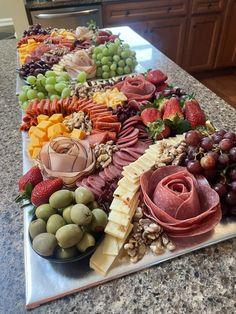 a platter filled with different types of cheeses and fruits on a kitchen counter