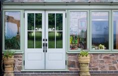 an image of a green house with potted plants in the front door and windows