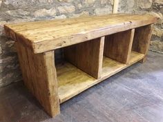 a wooden bench sitting in front of a stone wall next to a brick wall and floor