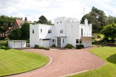 a large white house sitting on top of a lush green field