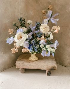 a vase filled with flowers sitting on top of a wooden block