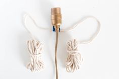 a cord connected to a light bulb on a white surface with a gold colored plug