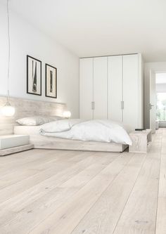 a bedroom with white walls and wooden floors