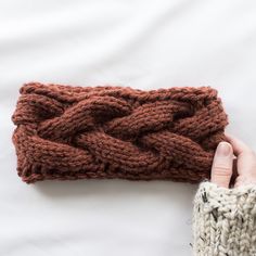 a knitted headband is being held by someone's hand