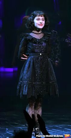 a woman in black dress standing on stage