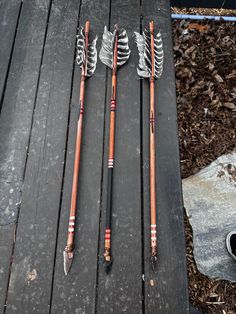 two arrows are laying next to each other on a wooden table with leaves around them