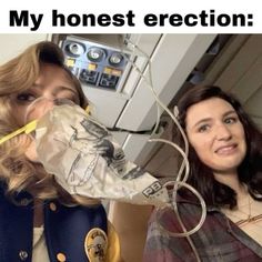 two women standing next to each other in front of a machine with wires wrapped around them