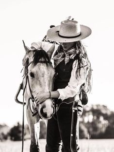 a woman with a cowboy hat is petting a horse