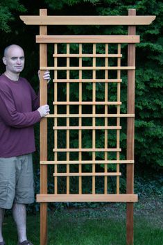 a man standing next to a wooden trellis