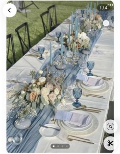 the table is set with blue and white plates, silverware, and flower centerpieces