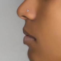 a woman's nose with a single diamond in the middle of her nose and an earring on it