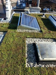 the roof is covered with green grass and rocks, while there are solar panels on top