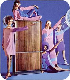 a group of women in pink dresses standing next to an old fashioned radio with the woman's legs on top of it