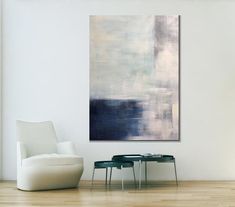 an abstract painting hangs on the wall next to two tables