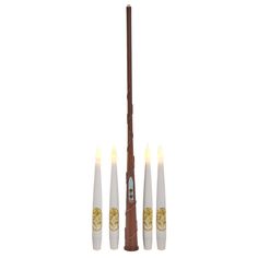 four white candles with gold designs on the top and one brown stick in the middle