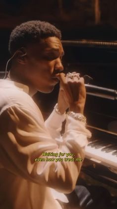 a man sitting in front of a piano with headphones on his ears and holding a microphone to his mouth