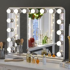 a lighted vanity mirror sitting on top of a white dresser next to a window with christmas decorations