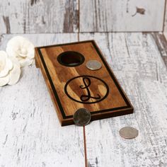 a wooden board with some coins and a flower on the table next to it,