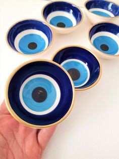 five blue and white bowls with an evil eye on the bottom one being held by a person's hand