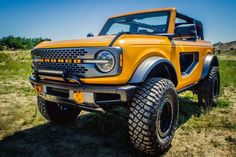 an orange truck parked on top of a grass covered field