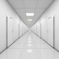 an empty white hallway with doors leading to another room in the center and light at the end