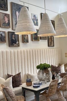 a dining room table with chairs and lamps hanging above it, along with pictures on the wall