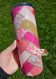 a person holding up a pink and gold glittered tumbler cup in their hand