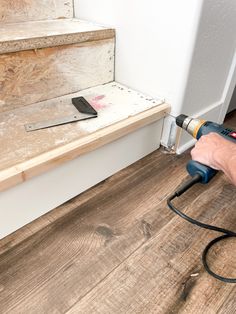 a person using a power drill to install wood flooring on the stairs in a house