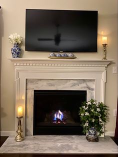 a fireplace with a flat screen tv above it and flowers on the mantle next to it