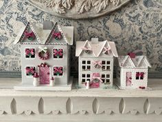 three small white houses with pink bows on them