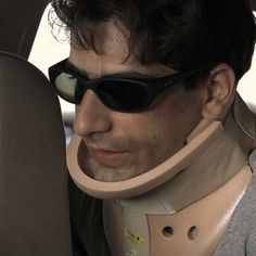 a man wearing sunglasses and a neck brace in the back seat of a car with a quote on it