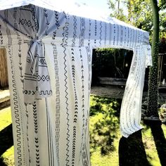 a white tent with black and white designs on it's side in the grass