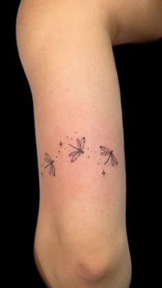 the back of a woman's arm with three dragonflies tattoo on her left side