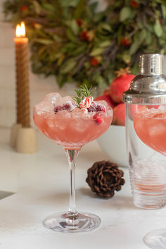 two glasses filled with pink liquid and garnished with cranberries sit on a table