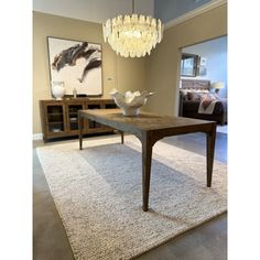 a dining room with a chandelier hanging from the ceiling and a rug on the floor