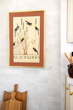 a kitchen with white cabinets and blackbirds on the wall above it is a wooden cutting board